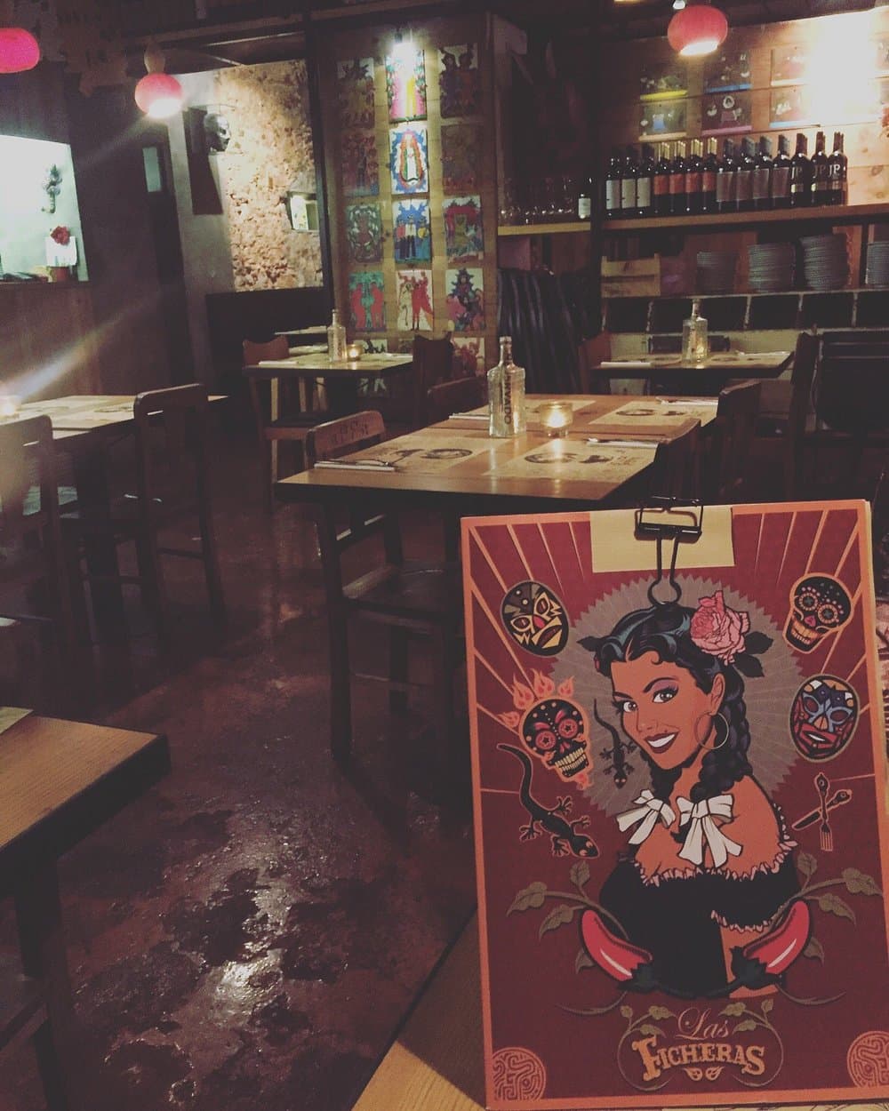 Las Ficheras dining room with folk-art wall tiles and a bottle-lined bar